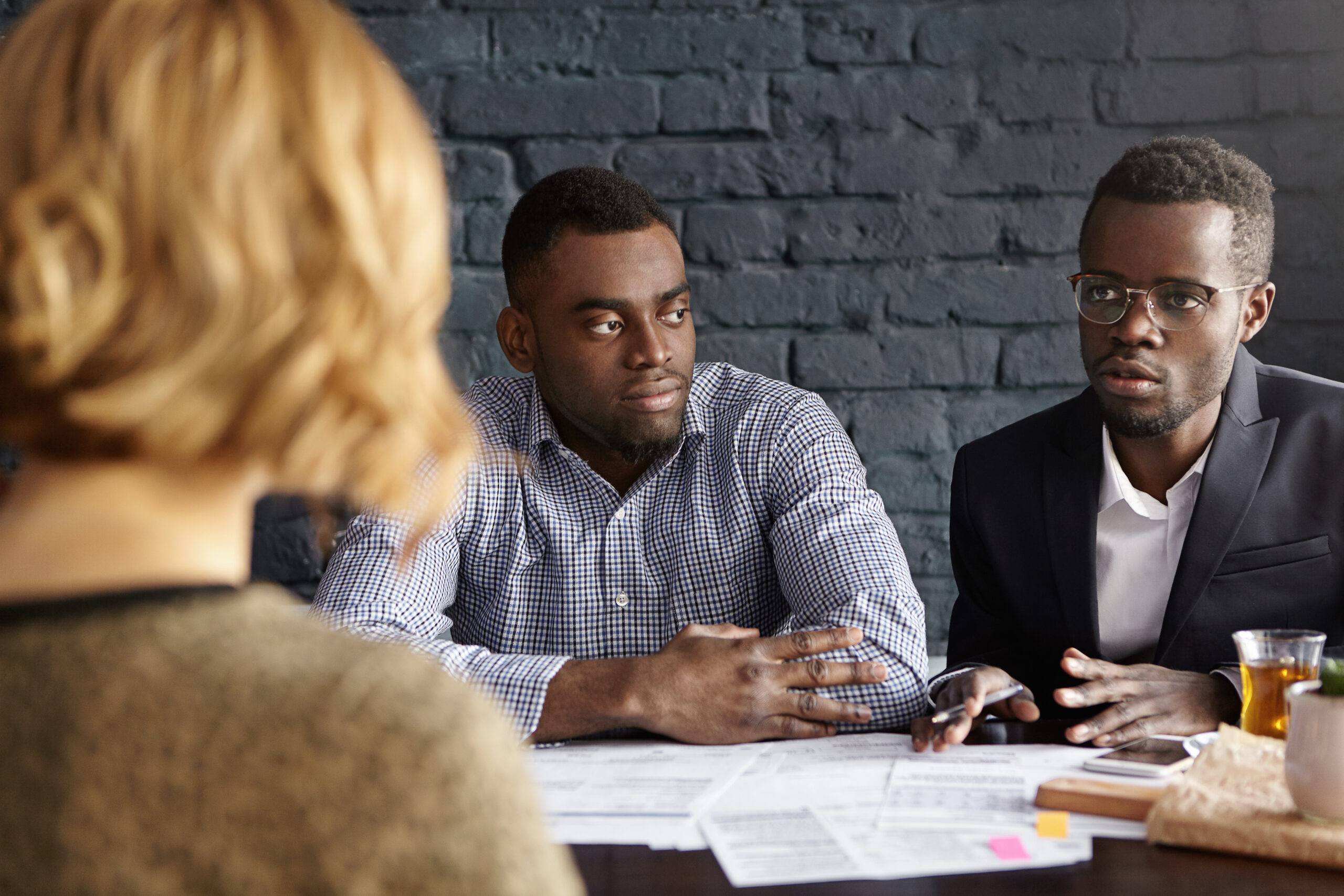 People, and career concept. Two sad dark-skinned executives having meeting with unrecognizable female, who working in their company, informing that they have to fire her because of reduction of staff