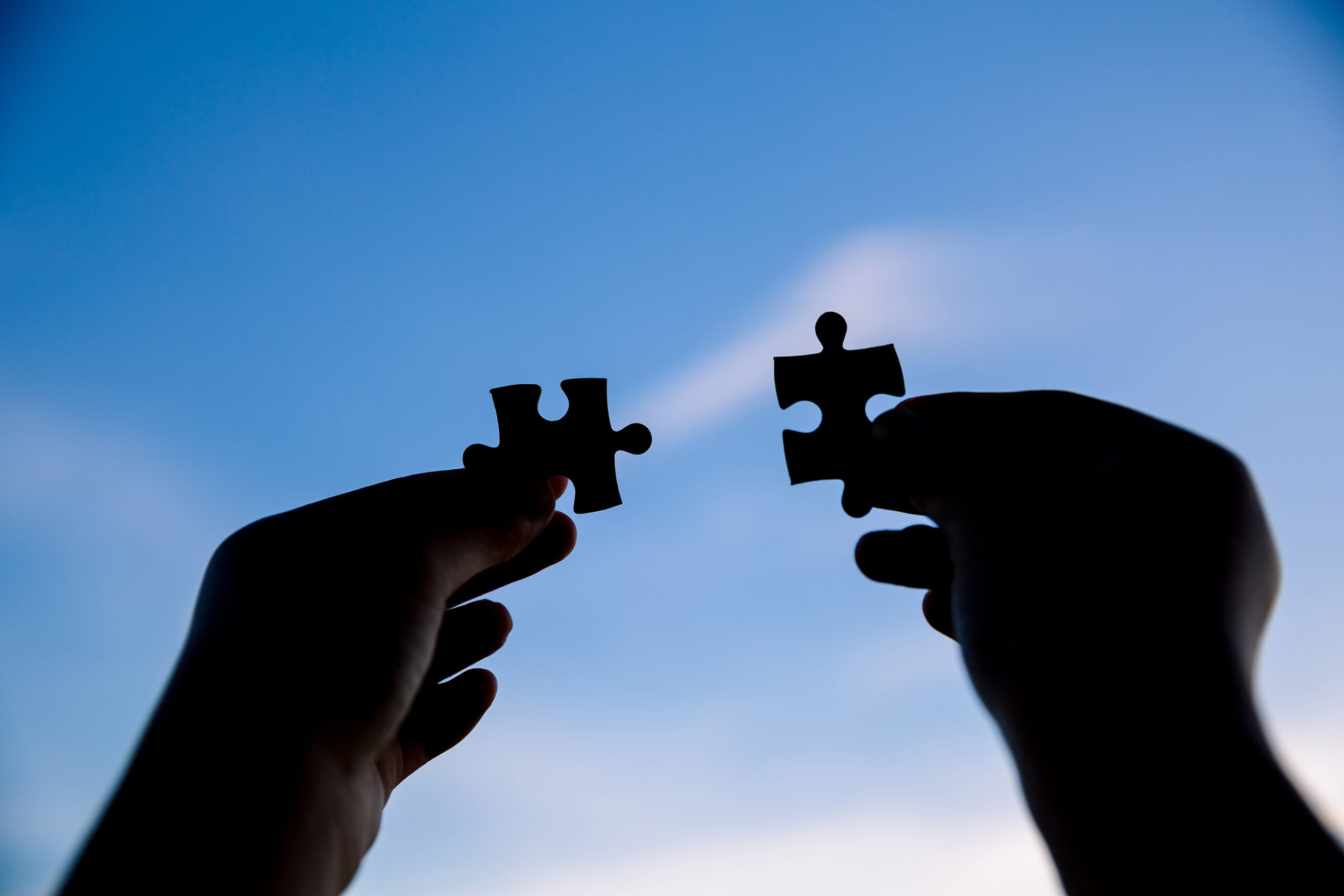 two hands trying to connect couple puzzle piece with sunset background. symbol of association and connection. business strategy.